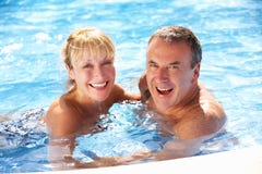 Couples aînés ayant l'amusement dans la piscine image stock Couples aînés ayant l'amusement dans la piscine image stock