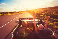 Couples conduisant le convertible au coucher du soleil Couples conduisant le convertible au coucher du soleil