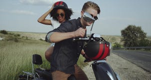 Couples des amis allant sur le tour avec une motocyclette et des casques rouges banque de vidéos Couples des amis allant sur le tour avec une motocyclette et des casques rouges banque de vidéos