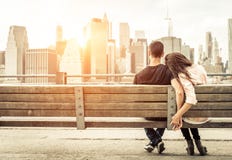Couples détendant sur le banc de New York devant l'horizon au soleil photo libre de droits Couples détendant sur le banc de New York devant l'horizon au soleil photo libre de droits
