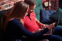 Couples heureux passant en revue l'Internet sur l'ordinateur portable tout en se reposant sur le Th photographie stock Couples heureux passant en revue l'Internet sur l'ordinateur portable tout en se reposant sur le Th photographie stock