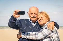 Couples heureux supérieurs prenant un selfie à la plage image stock Couples heureux supérieurs prenant un selfie à la plage image stock