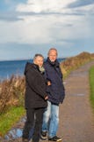 Couples mûrs heureux détendant des dunes de mer baltique image stock Couples mûrs heureux détendant des dunes de mer baltique image stock