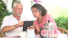 Couples mûrs utilisant la Tablette de Digital au Tableau de petit déjeuner clips vidéos Couples mûrs utilisant la Tablette de Digital au Tableau de petit déjeuner clips vidéos