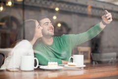 Couples mignons prenant le selfie dans un café photos stock Couples mignons prenant le selfie dans un café photos stock