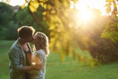 Couples romantiques s'embrassant au coucher du soleil en parc Photographie stock libre de droits Couples romantiques s'embrassant au coucher du soleil en parc Photographie stock libre de droits