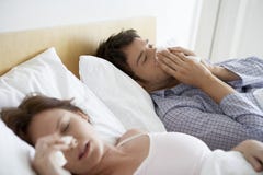 Couples souffrant des froids dans le lit images stock Couples souffrant des froids dans le lit images stock
