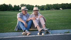 Couples supérieurs élégants se reposant avec une planche à roulettes clips vidéos Couples supérieurs élégants se reposant avec une planche à roulettes clips vidéos