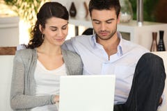 Couples utilisant l'ordinateur portatif à la maison image libre de droits Couples utilisant l'ordinateur portatif à la maison image libre de droits