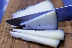 Coupure du fromage avec un couteau sur un panneau en bois de métier images stock Coupure du fromage avec un couteau sur un panneau en bois de métier images stock