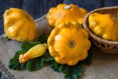 Courge trois pattypan jaune avec la feuille et la fleur sur une table en bois foncée Photos stock Courge trois pattypan jaune avec la feuille et la fleur sur une table en bois foncée Photos stock