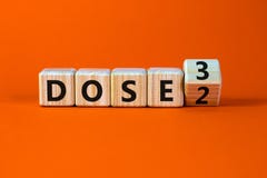 Covid-19 booster dose vaccine shot symbol. Turned a wooden cube and changed words dose 2 to dose 3. Beautiful orange table, orange