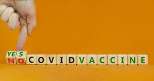 Covid vaccine yes or no symbol. Doctor turns cubes and changes words `covid vaccine no` to `covid vaccine yes`. Beautiful oran