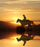Cowboy de coucher du soleil par un lac dans les montagnes photographie stock libre de droits Cowboy de coucher du soleil par un lac dans les montagnes photographie stock libre de droits