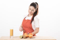 Cozimento vestindo estando do avental da jovem mulher, cortando o fruto em uma placa fotos de stock Cozimento vestindo estando do avental da jovem mulher, cortando o fruto em uma placa fotos de stock