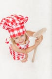Cozinheiro chefe pequeno com avental e chapéu que guarda uma grande colher de madeira - lo Fotografia de Stock Cozinheiro chefe pequeno com avental e chapéu que guarda uma grande colher de madeira - lo Fotografia de Stock
