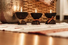 Cozy home interior decor, burning candles on a multi-colored rug on the background of a wicker straw box - Image stock image Cozy home interior decor, burning candles on a multi-colored rug on the background of a wicker straw box - Image stock image