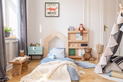 Cozy kids bedroom with blue bedding and warm blanket on the bed, real photo with mockup poster on the floor