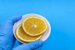 Сочные апельсины на плите Руки в голубых перчатках стоковые изображения Сочные апельсины на плите Руки в голубых перчатках стоковые изображения