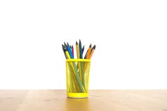 Crayons de couleur dans un verre jaune sur une table en bois sur un fond blanc photographie stock libre de droits Crayons de couleur dans un verre jaune sur une table en bois sur un fond blanc photographie stock libre de droits