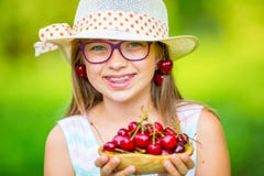 Criança com cerejas Menina com cerejas frescas Cintas e vidros vestindo dos dentes da menina loura caucasiano bonito nova fotografia de stock royalty free Criança com cerejas Menina com cerejas frescas Cintas e vidros vestindo dos dentes da menina loura caucasiano bonito nova fotografia de stock royalty free