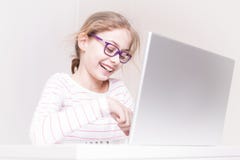 Criança de sorriso feliz da menina da criança que usa o laptop imagens de stock royalty free Criança de sorriso feliz da menina da criança que usa o laptop imagens de stock royalty free