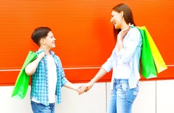 A criança de sorriso feliz da mãe e do filho com sacos de compras está tendo o divertimento fotos de stock A criança de sorriso feliz da mãe e do filho com sacos de compras está tendo o divertimento fotos de stock