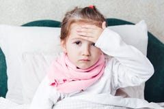 A criança doente que encontra-se na cama e toca nela forehaed imagens de stock A criança doente que encontra-se na cama e toca nela forehaed imagens de stock