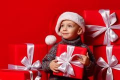 Criança engraçada de sorriso no chapéu vermelho de Santa que mantém o presente do Natal disponivel Conceito do Natal fotos de stock royalty free Criança engraçada de sorriso no chapéu vermelho de Santa que mantém o presente do Natal disponivel Conceito do Natal fotos de stock royalty free