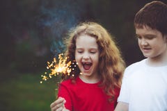 Criança feliz do amigo no partido com o chuveirinho ardente em sua mão imagens de stock Criança feliz do amigo no partido com o chuveirinho ardente em sua mão imagens de stock