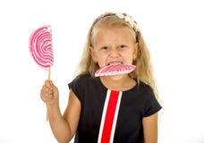 Criança fêmea pequena bonita com olhos azuis doces e cabelo louro longo que come doces enormes da espiral do pirulito Imagens de Stock Royalty Free Criança fêmea pequena bonita com olhos azuis doces e cabelo louro longo que come doces enormes da espiral do pirulito Imagens de Stock Royalty Free