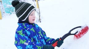 Criança pequena bonito que ajuda a escovar uma neve de um carro O menino da criança que usa a ferramenta para limpar gena o carro imagem de stock royalty free Criança pequena bonito que ajuda a escovar uma neve de um carro O menino da criança que usa a ferramenta para limpar gena o carro imagem de stock royalty free