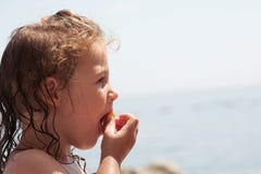 Criança que come um petisco e que aprecia a opinião da praia fotografia de stock Criança que come um petisco e que aprecia a opinião da praia fotografia de stock
