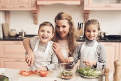 Crianças com a mãe na cozinha A mãe está ajudando crianças prepara vegetais para a salada imagem de stock Crianças com a mãe na cozinha A mãe está ajudando crianças prepara vegetais para a salada imagem de stock