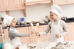 Crianças na cozinha O irmão e a irmã estão lutando com colheres imagens de stock royalty free Crianças na cozinha O irmão e a irmã estão lutando com colheres imagens de stock royalty free