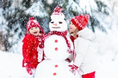 Crianças que constroem o boneco de neve Crianças na neve Divertimento do inverno imagem de stock royalty free Crianças que constroem o boneco de neve Crianças na neve Divertimento do inverno imagem de stock royalty free
