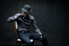 The criminal and robber in black gloves are sitting on a chair royalty free stock photography The criminal and robber in black gloves are sitting on a chair royalty free stock photography