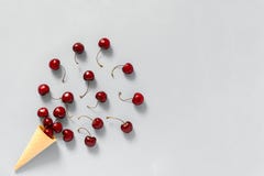 Crispy waffle ice cream cone with scattered red ripe sweet cherries. Still life on grey background. Copy space, Flat lay, Top view stock photo Crispy waffle ice cream cone with scattered red ripe sweet cherries. Still life on grey background. Copy space, Flat lay, Top view stock photo
