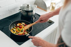 cropped shot of man cooking vegetables in frying pan on electric stove royalty free stock photos cropped shot of man cooking vegetables in frying pan on electric stove royalty free stock photos