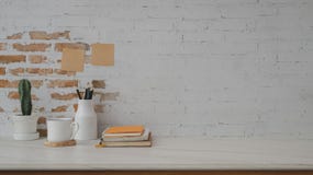Cropped Shot Of  Workspace With Books, Coffee Cup, Ceramic Decorations And Copy Space On Marble Desk With Brick Wall Royalty Free Stock Photos