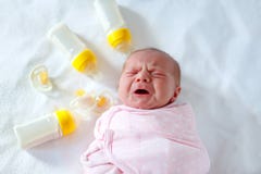 Crying newborn baby girl with nursing bottles. Bottle feeding Stock Photos Crying newborn baby girl with nursing bottles. Bottle feeding Stock Photos