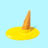 Crème glacée jaune fondue de fruit dans un klaxon de gaufre sur un fond bleu-clair Humeur d'été Concept créateur images libres de droits Crème glacée jaune fondue de fruit dans un klaxon de gaufre sur un fond bleu-clair Humeur d'été Concept créateur images libres de droits