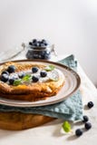 Crêpe néerlandaise faite maison de bébé avec les myrtilles, la menthe et le sucre en poudre Copiez l'espace photographie stock libre de droits Crêpe néerlandaise faite maison de bébé avec les myrtilles, la menthe et le sucre en poudre Copiez l'espace photographie stock libre de droits
