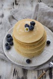 Crêpes avec des myrtilles du plat blanc et serviette grise avec la fourchette au fond en bois blanc photos stock Crêpes avec des myrtilles du plat blanc et serviette grise avec la fourchette au fond en bois blanc photos stock