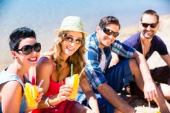 Cuatro amigos que se sientan en la playa del lago con los cócteles imagenes de archivo Cuatro amigos que se sientan en la playa del lago con los cócteles imagenes de archivo