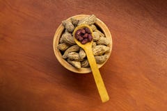 Cuenco con los cacahuetes con la c?scara y pelados con una cuchara en una superficie de madera imagen de archivo libre de regalías Cuenco con los cacahuetes con la c?scara y pelados con una cuchara en una superficie de madera imagen de archivo libre de regalías