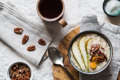 Cuenco de las gachas de avena del desayuno con las nueces y el té de la fruta fotos de archivo libres de regalías Cuenco de las gachas de avena del desayuno con las nueces y el té de la fruta fotos de archivo libres de regalías