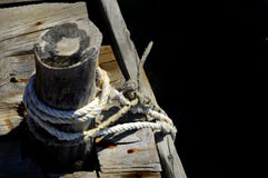 Cuerda y nudo en un embarcadero de madera en la playa - backgound negro del marinero para escribir fotografía de archivo Cuerda y nudo en un embarcadero de madera en la playa - backgound negro del marinero para escribir fotografía de archivo