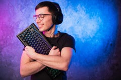 Cuffia avricolare d'uso del gamer nerd con la tastiera degli abbracci del microfono Concetto di dipendenza del gioco fotografie stock Cuffia avricolare d'uso del gamer nerd con la tastiera degli abbracci del microfono Concetto di dipendenza del gioco fotografie stock