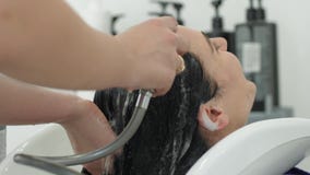 Cuidados capilares profissionais, cabeça de lavagem do cliente no dissipador sob o chuveiro no estúdio da beleza filme Cuidados capilares profissionais, cabeça de lavagem do cliente no dissipador sob o chuveiro no estúdio da beleza filme